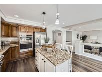 Bright kitchen featuring granite counters, island with seating, and stainless steel appliances at 5072 Cathay St, Denver, CO 80249