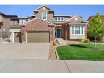 Charming two-story home featuring a brick facade, well-manicured lawn, and two-car garage at 3745 Spanish Oaks Trl, Castle Rock, CO 80108