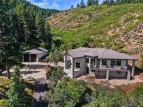Stunning mountain home with a large deck and a detached garage surrounded by lush greenery at 6123 Buffalo Run, Littleton, CO 80125
