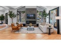 Bright living room features a fireplace, hardwood floors, modern furniture, and ample natural light from expansive windows at 6123 Buffalo Run, Littleton, CO 80125
