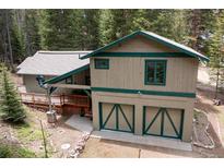 Mountain home with a two-car garage, deck, and forest surroundings at 446 Blue River Rd, Breckenridge, CO 80424