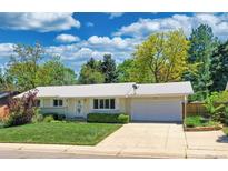 Charming ranch-style home featuring a well-manicured lawn, mature trees, and a spacious driveway and garage at 6684 E Bates Ave, Denver, CO 80224