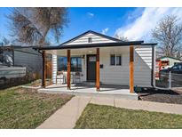 Charming home with a covered front porch, wooden support beams, and a well-maintained lawn at 1947 Jay St, Lakewood, CO 80214