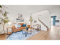 Bright living room features a brown leather couch, eye-catching decor, and a staircase leading upstairs at 10311 E Evans Ave # 132, Aurora, CO 80247