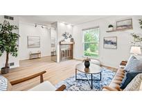 Bright living room with a fireplace, a large window, light wood floors and contemporary decor at 10311 E Evans Ave # 132, Aurora, CO 80247