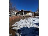 Charming single-story home with a covered porch, a lawn with snowy patches and mature trees at 13430 Green Cir, Broomfield, CO 80020