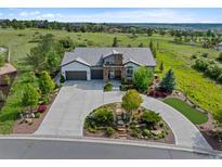 Expansive home with landscaped front yard, circular driveway, and inviting curb appeal on a beautiful sunny day at 5608 Raintree Dr, Parker, CO 80134