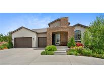 Charming stucco home with a stone archway and three-car garage, set in a landscaped front yard at 5608 Raintree Dr, Parker, CO 80134