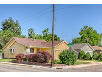 Charming yellow home with lush landscaping and a well-maintained yard on a sunny corner lot at 3100 S Corona St, Englewood, CO 80113