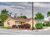 Charming yellow house featuring a well-maintained lawn and landscaping with mature bushes at 3100 S Corona St, Englewood, CO 80113