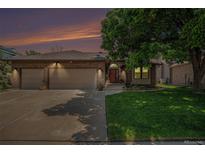 Charming brick home with a well-manicured lawn, mature tree, and attached three-car garage at 1152 Clubhouse Dr, Broomfield, CO 80020