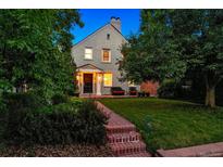 Charming two-story home with a brick walkway, lush landscaping, and inviting front porch seating at 428 N Humboldt St, Denver, CO 80218
