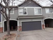 Charming townhome featuring attached two-car garage and mature trees on a cloudy day at 1461 S Danube Way # 104, Aurora, CO 80017