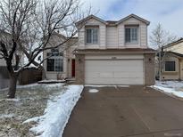 Two-story home with a two-car garage, brick accents, and a well-maintained front yard during winter at 4105 N Dunkirk Ct, Denver, CO 80249