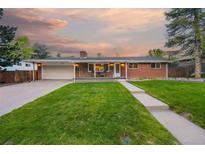 Charming brick home featuring a well-manicured lawn, covered porch, and attached garage at 6013 S Logan St, Centennial, CO 80121