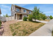 Two-story home with a manicured lawn, natural rock ground cover and a welcoming porch at 19047 Randolph Pl, Denver, CO 80249