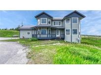 Charming two-story home with a covered porch, gray siding, and dark blue accents at 43793 Buckskin Rd, Parker, CO 80138
