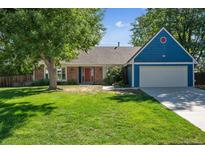 Ranch style home with blue siding, red door, and a well-manicured lawn at 3824 S Xenia St, Denver, CO 80237