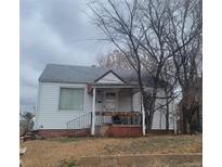 Charming single-story home featuring white siding, a cozy front porch, and mature trees in the front yard at 4871 Alcott St, Denver, CO 80221