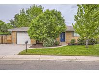 Charming brick home with a well-manicured lawn, a blue front door, and an attached garage at 6046 Vrain St, Arvada, CO 80003