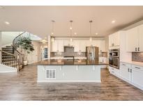 Well-lit kitchen features a central island with modern appliances and staircase at 1715 Pioneer Cir, Lafayette, CO 80026