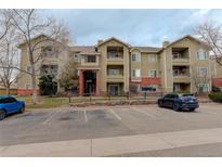 Apartment building exterior showing parking spots, muted green walls and brick accents at 8422 S Upham Way # H75, Littleton, CO 80128