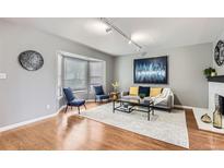 Cozy living room with a bay window, hardwood floors, and stylish decor, perfect for relaxation and entertaining at 7114 E Briarwood Dr, Centennial, CO 80112