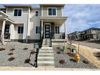 Inviting two-story home with a covered porch, black railings, and low-maintenance gravel landscaping at 4598 S Versailles St # B, Aurora, CO 80015