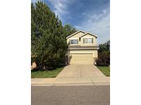 Charming two-story home with a well-maintained lawn, complemented by a mature tree and a spacious two car garage at 10386 Ravenswood Way, Highlands Ranch, CO 80130