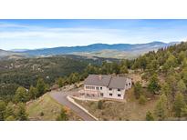 Stunning home boasts serene mountain views from a private, elevated location with a deck and a circular driveway at 5197 Bear Mountain Dr, Evergreen, CO 80439