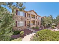 Charming multi-level condo featuring a stone facade, private balconies, and lush landscaping at 7160 S Wenatchee Way # F, Aurora, CO 80016