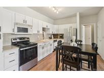 Well-lit kitchen featuring white cabinets, stainless steel appliances, and adjacent dark wood dining table at 7160 S Wenatchee Way # F, Aurora, CO 80016