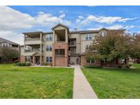 A beautiful exterior view of the building with a well-manicured lawn and blue skies above at 12816 Ironstone Way # 203, Parker, CO 80134