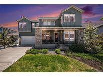Inviting two-story home with a stone facade, manicured lawn, and a welcoming front porch at 9380 Bear River St, Littleton, CO 80125