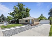 Charming single-story home features a well-manicured lawn, a detached garage, and a brick exterior at 2582 S Uno Way, Denver, CO 80219