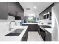 Modern kitchen features sleek gray cabinets, stainless steel appliances, and white countertops that overlook the living area at 5955 E 10Th Ave # 507, Denver, CO 80220
