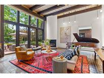 Bright living room featuring a fireplace, piano, large windows, and comfortable seating area at 50 Albion St, Denver, CO 80220