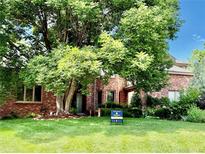 Charming red brick home with lush green lawn, mature trees, and 'For Sale' sign at 8461 Pawnee Ln, Niwot, CO 80503