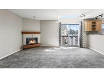 Bright living room with fireplace, balcony, and neutral carpet at 6380 S Boston St # 397, Greenwood Village, CO 80111