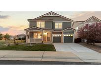 Charming two-story home featuring a welcoming front porch and a well-maintained lawn at sunset at 1983 Candleglow St, Castle Rock, CO 80109