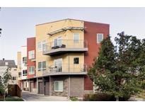 Modern townhouse showcases yellow and maroon facade, multiple balconies, and attached garages at 947 S Washington St, Denver, CO 80209