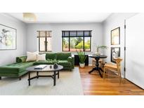 Bright living room featuring a comfortable green sofa, hardwood floors, and large windows with natural light at 1160 Birch St # 22, Denver, CO 80220