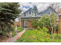 Charming home featuring a colorful front yard garden, mature trees, and a welcoming walkway at 2514 N Humboldt St, Denver, CO 80205