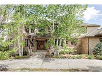 Charming brick home featuring a beautiful stone walkway, lush landscaping, and mature aspen trees at 5550 Preserve Dr, Greenwood Village, CO 80121