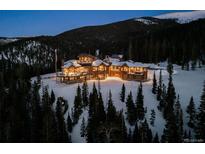 Stunning mountain estate features a log cabin design and beautiful landscaping surrounded by snow-covered trees at 300 Little Sallie Barber Trl, Breckenridge, CO 80424