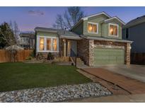 Charming two-story home featuring a stone facade, green siding, well-maintained lawn, and a two-car garage at 13199 Ash St, Thornton, CO 80241