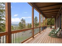 Covered deck with mountain views and wooden floors at 13012 S Wamblee Valley Rd, Conifer, CO 80433