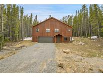 Beautiful wood-sided home with a large garage, situated among tall pine trees and a gravel driveway at 79 Beaver Rd, Idaho Springs, CO 80452