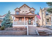 Charming two-story home with a welcoming front porch, lush landscaping, and an American flag at 537 N Logan St, Denver, CO 80203