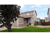 Charming two-story home with a well-maintained lawn, attached garage, and American flag on the front porch at 765 Mockingbird St, Brighton, CO 80601
